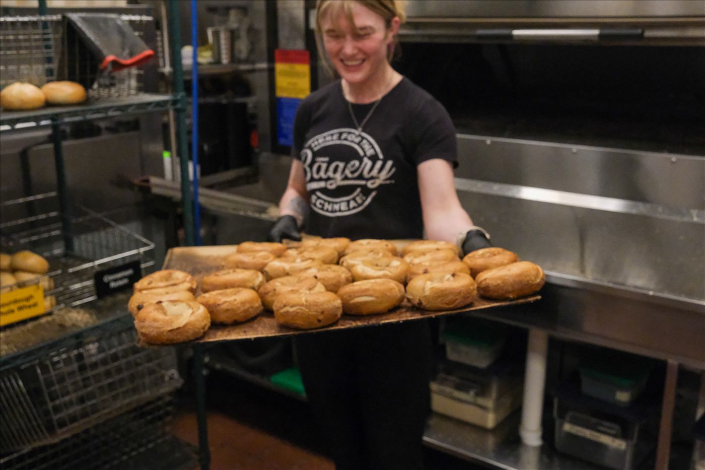 A baker carrying a tray of fresh bagels