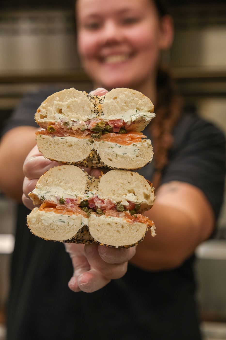 Team member holding up a stack of bagel sandwiches